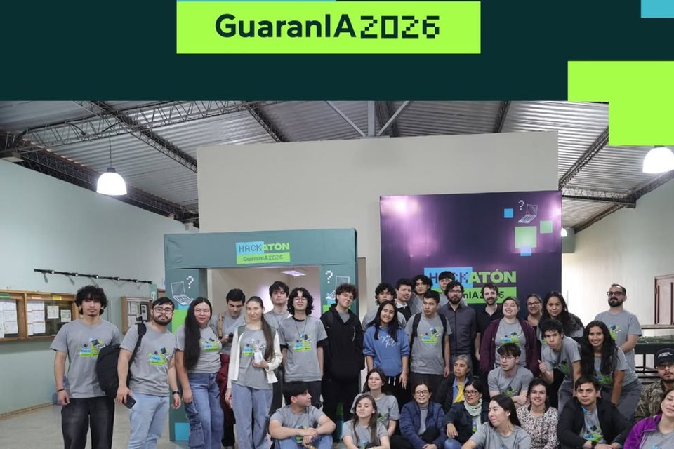 Participants of Hackatón GuaranIA 2026 in matching T-shirts, posing in front of the event backdrop.