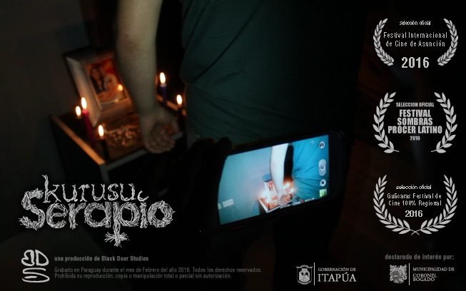 Afiche del cortometraje Kurusu Serapio: una mano sostiene un teléfono encendido junto a unas velas, con laureles de festivales.